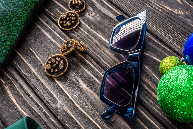 Close Up View Of Stylish Sunglasses And Earrings On Wooden Tabletop